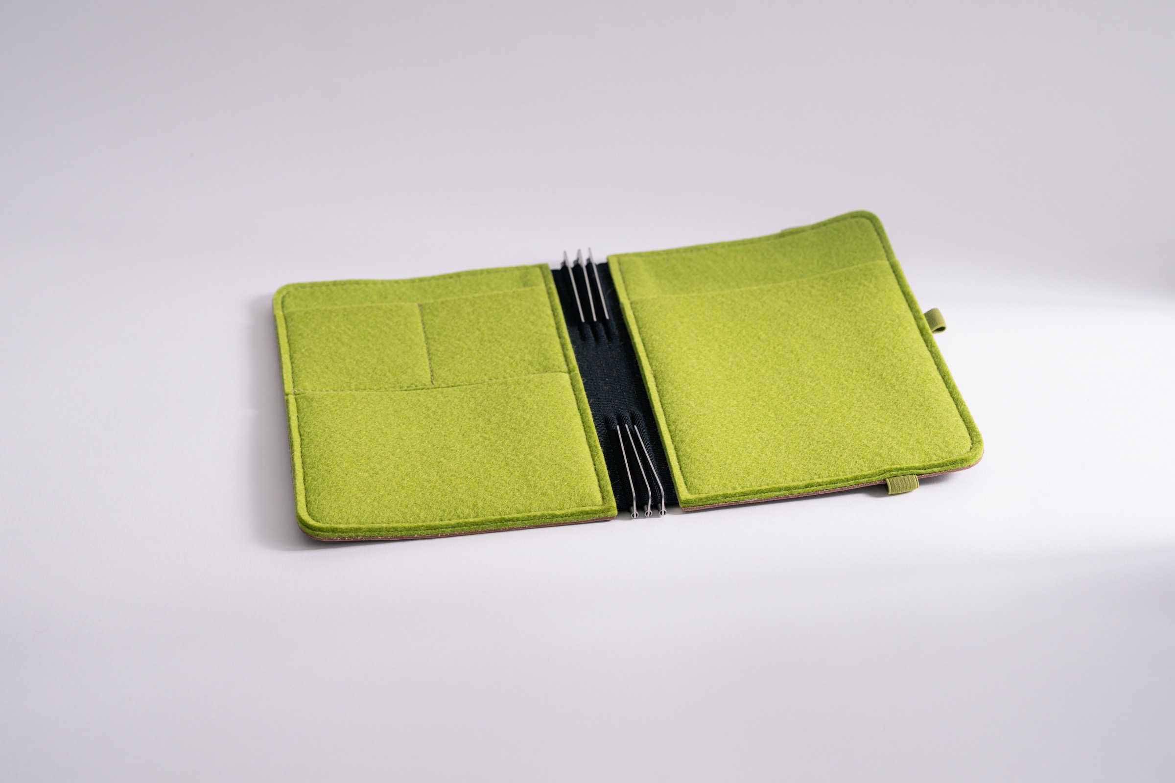 Taschenbegleiter LTD_030 im Format M, mit lindgrünem Filz innen und dunkelbraunem Leder außen mit Verschlussgummi.