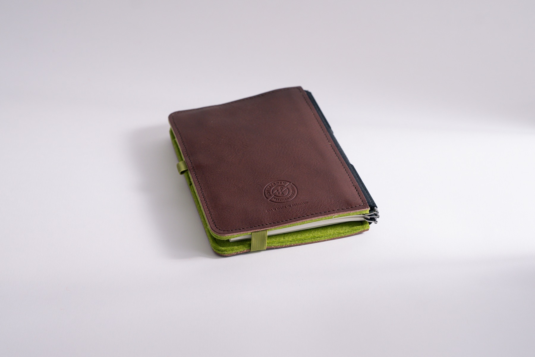 Taschenbegleiter LTD_030 im Format M, mit lindgrünem Filz innen und dunkelbraunem Leder außen mit Verschlussgummi.