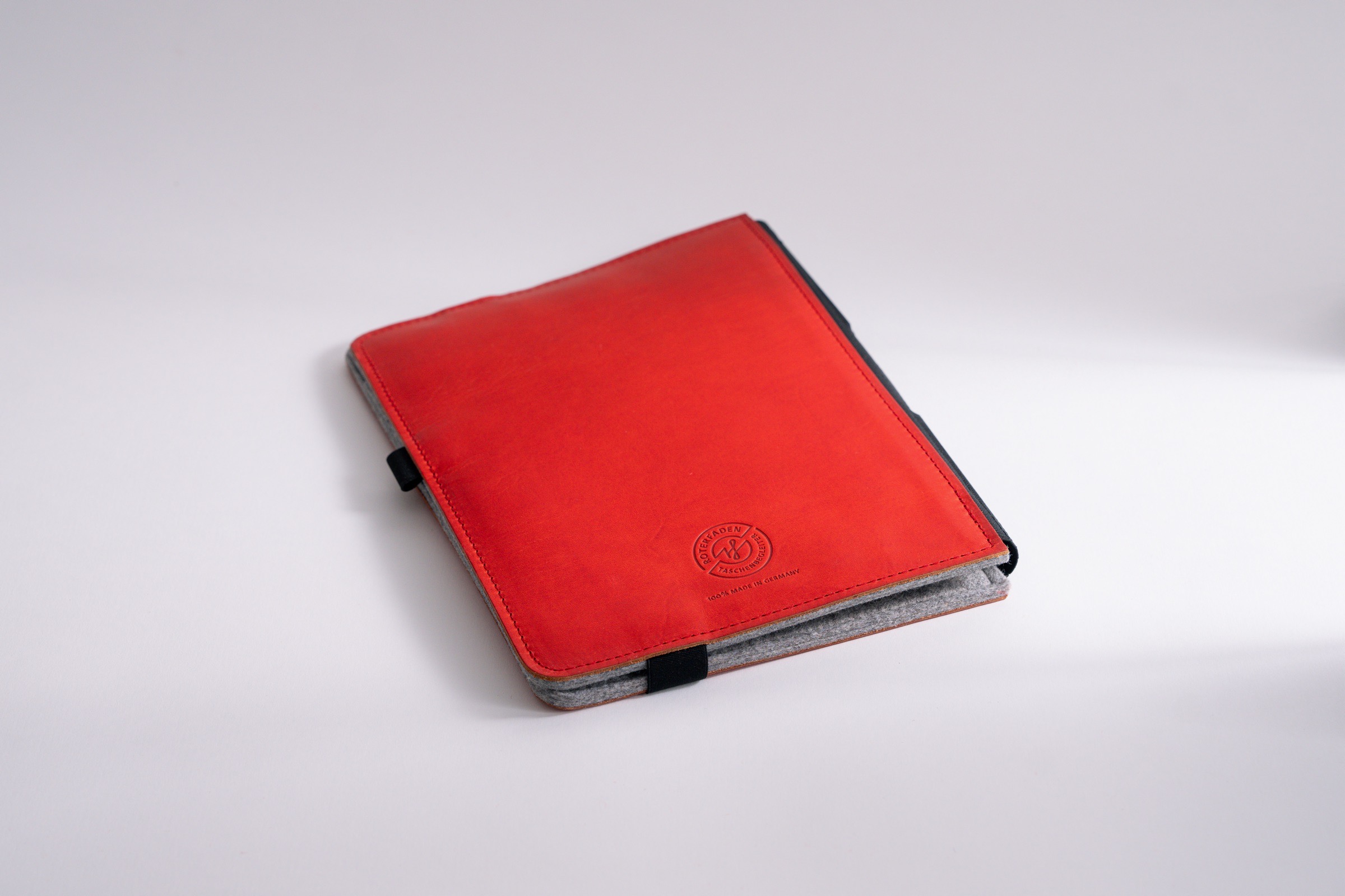 Taschenbegleiter LTD_028 in hellgrauem Filz innen und rotem Filz außen, mit nach innen versetzten Klammern für Notizbücher und lose Blätter.